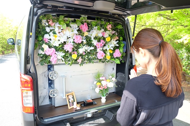 火葬車で愛犬を見送る女性