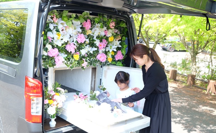 火葬車でお見送りをする親子